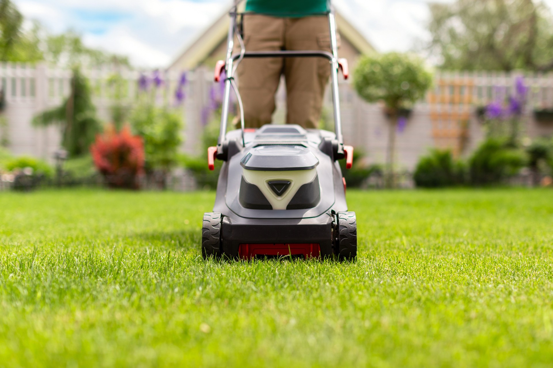 Modern lawn mower. Grass clippings get spewed out of a mower pushed around by male gardener working with mower machine Modern lawn mower. Grass clippings get spewed out of a mower pushed around by male gardener working with mower machine